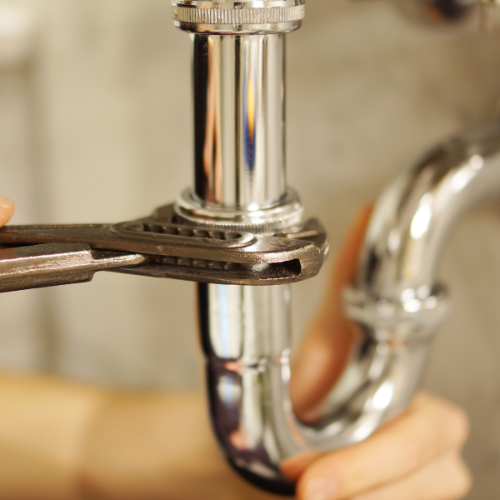 A close-up of a wrench tightening a pipe.