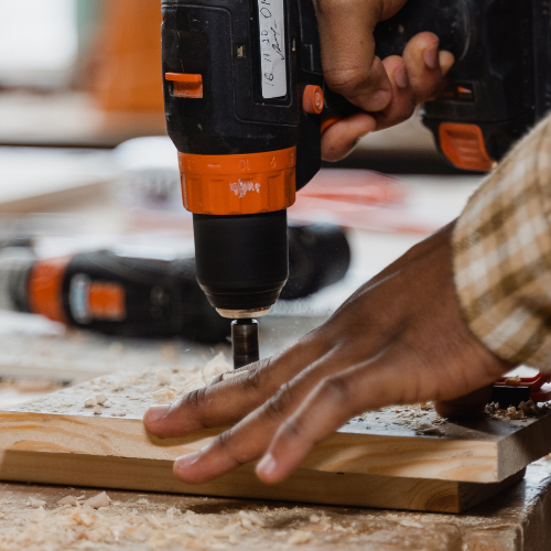 A power drill being used to screw hardware into a piece of wood.