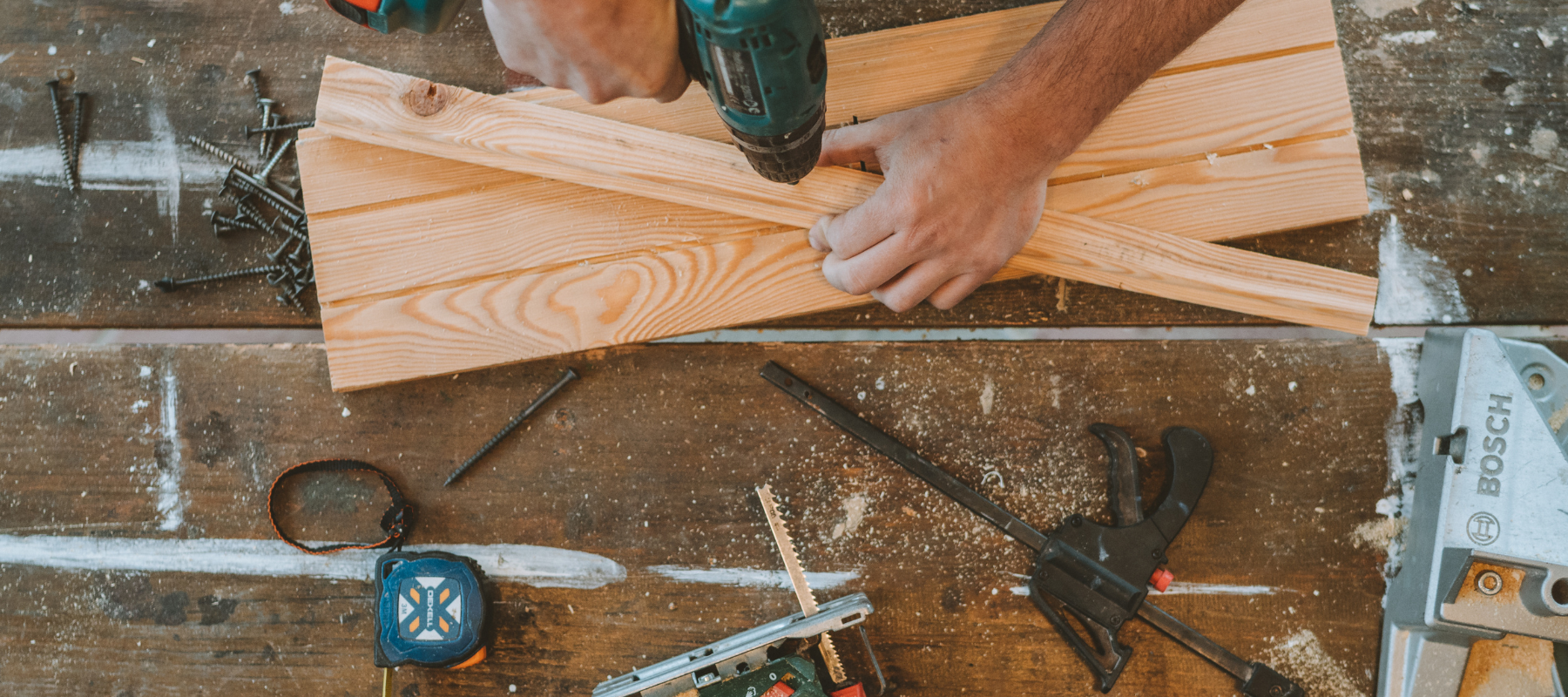 An arial view of a power drill being used to put hardware into a piece of wood.